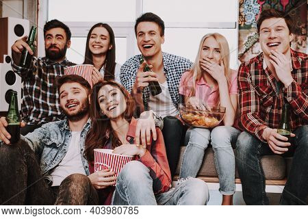 Group Of Friends Gathering Around Coffee Table At Home. Friends Gathered At The Table And Drinking B