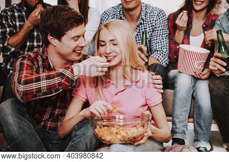 Group Of Friends Gathering Around Coffee Table At Home. Friends Gathered At The Table And Drinking B