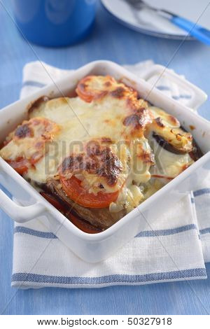 Moussaka in a baking dish under white sauce