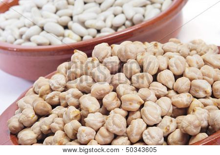 closeup of some earthenware bowls with dry chickpeas and white beans