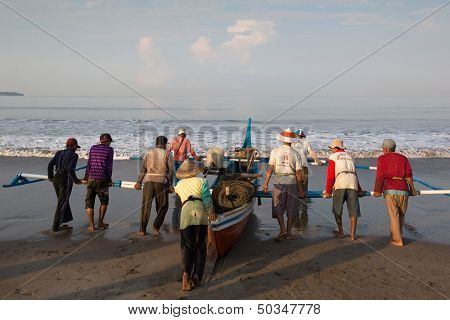 PADANG - AUGUST 25: Fishermen work as a team launch the boat to sea in Padang, West Sumatera, Indonesia on August 25, 2013. Resources from the sea is a major revenue earner. 