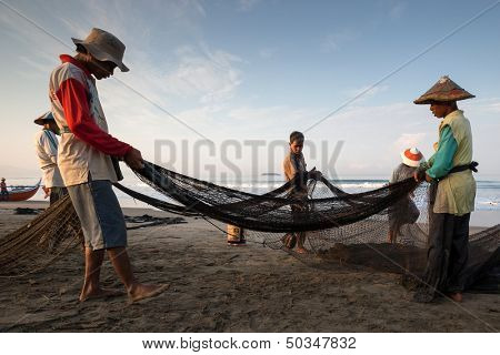 PADANG - AUGUST 25: Fishermen work as a team pull in the fishing nets from the sea in Padang, West Sumatera, Indonesia on August 25, 2013. Resources from the sea is a major revenue earner.  