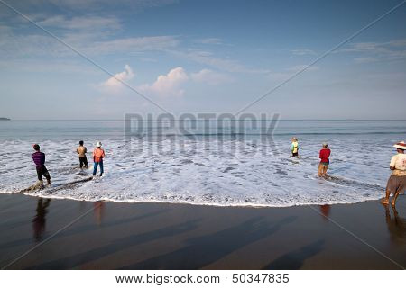 PADANG - AUGUST 25: Fishermen work as a team pull in the fishing nets from the sea in Padang, West Sumatera, Indonesia on August 25, 2013. Resources from the sea is a major revenue earner.  