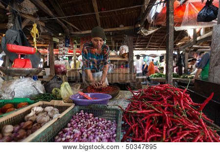 PADANG - AUGUST 25: A vendor grinds up fresh chili, pepper and spices for sale at her stall at an outdoor village market in Padang, West Sumatera, Indonesia on August 25, 2013. 