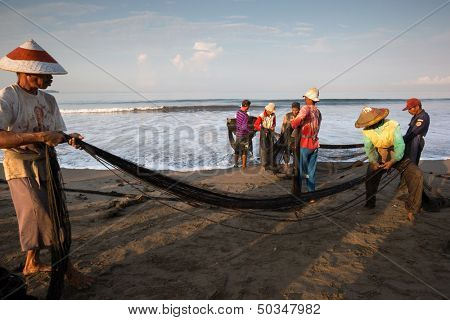 PADANG - AUGUST 25: Fishermen work as a team pull in the fishing nets from the sea in Padang, West Sumatera, Indonesia on August 25, 2013. Resources from the sea is a major revenue earner.  