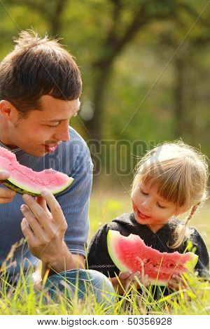 Father And Young Daughter Eat Watermelon In Nature