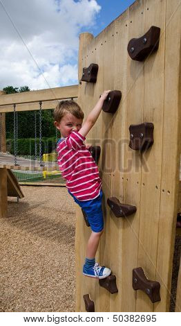 Young boy scaling climbing wall