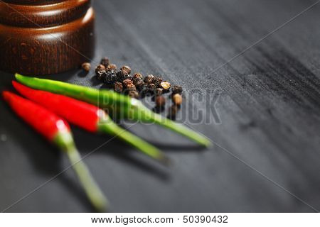 Wooden peppermill with pepper on black table