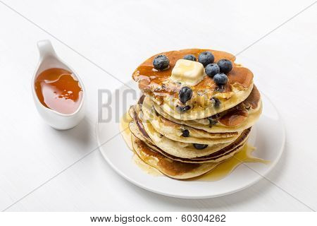 Big Pile of American Blueberry Pancakes with Berries and Maple Syrup
