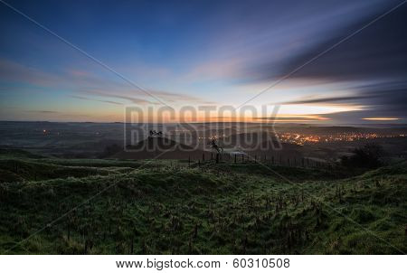 Beautiful Sunrise Dawn Landscape Of Hills Overlooking Brightly Lit Town In Valley Below