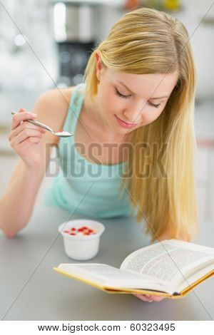 Young Woman Eating Yogurt And Reading Book