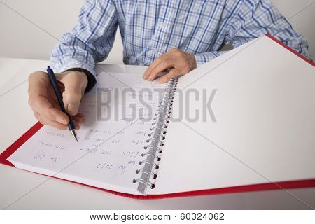 Midsection of senior businessman writing in file at desk