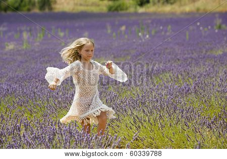 Beautiful young girl runs and jumps in the middle of a purple field of lavender