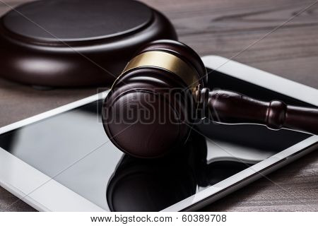 judge gavel and tablet computer on brown wooden backgroundjudge gavel and tablet computer on the tab