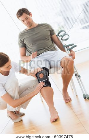 Female physiotherapist checking man with crutches in hospital