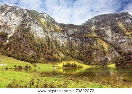 Cloudy day in the Bavarian lake Koenigssee. Clouds and mountains reflected in the water
