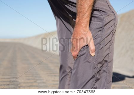 Active senior man touching his injured calf on a sunny day