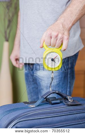 Man checking luggage weight with steelyard balance