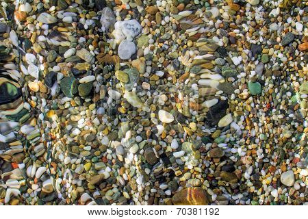 Small Sea Stones On The Seashore, Covered With A Sea Wave.