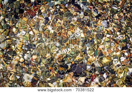 Small Sea Stones On The Seashore, Covered With A Sea Wave.