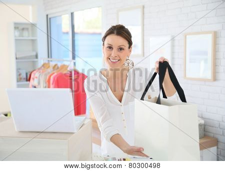 Seller in clothing store giving bag to customer