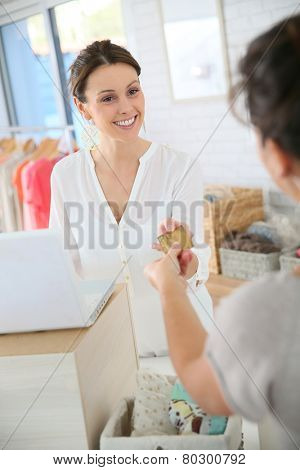 Customer in clothing store giving credit card to saleswoman