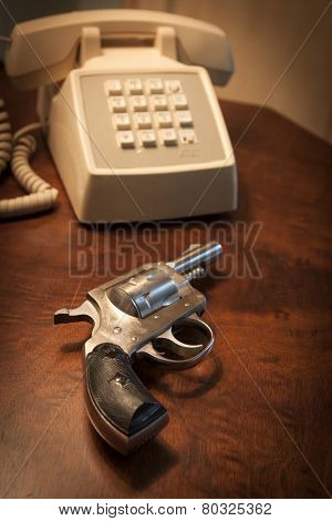 MARYLAND, USA - CIRCA DEC 2014: A staged close-up of an H & R .32 caliber pistol next to a telephone on a brown wooden nightstand table, shallow depth of field.