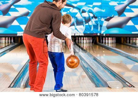 Father and son playing in bowling center