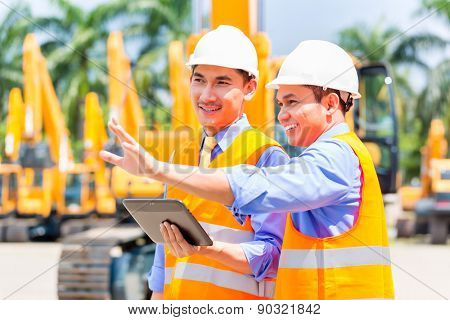 Asian engineer controlling construction machinery of construction site or mining company