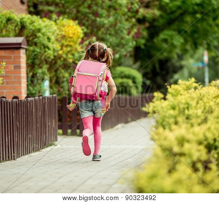 little girl with a backpack going to school. back view