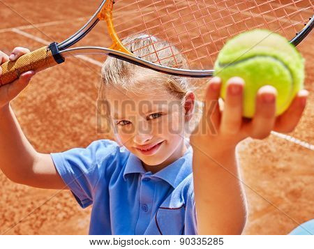 Child girl with racket and ball on  tennis court. 