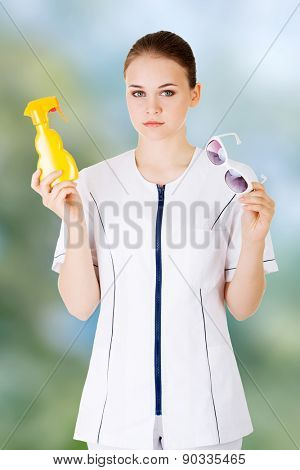 Young female doctor showing sunscreen and sun glasses.