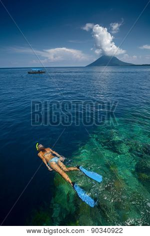 Lady snorkeling over reef wall in the area of the island of Bunaken, Sulawesi, Indonesia