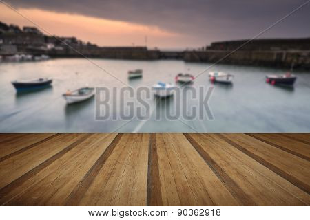 A traditional Cornish fishing village before sunrise with wooden foreground