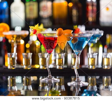 Martini drinks served on bar counter with blur bottles on background