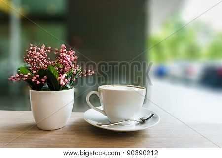 Coffee Cup And Flower On Wooden Table In Coffee Shop