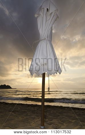 Beach Umbrella On Deserted Coast Sea At Sunrise