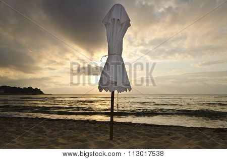 Beach Umbrella On Deserted Coast Sea At Sunrise