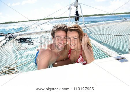 Cheerful couple relaxing on catamaran net