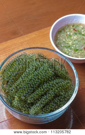 Seaweed Salad On A Wooden Floor With Seafood Sauce. Marine Algae, Sea Grapes Healthy Diet.