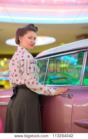 Beautiful girl in blouse with red lips near the pink car at bar