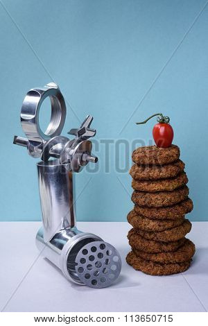 Burger beef steak cutlets and meat mincer on turquoise background.