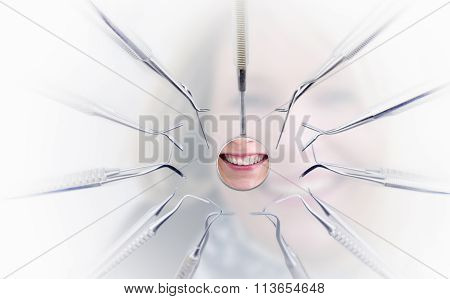 Dentist Mirror With Reflection Of Woman's Teeth And Dentist Tools