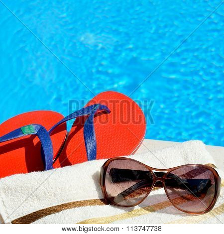 Sunglasses, Beach Towel And Flip-flops By The Swimming Pool.