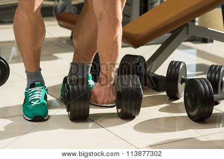 Bodybuilder picks up dumbbells.