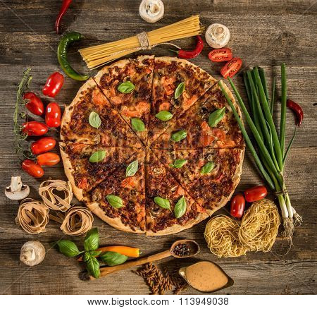 Italian food background with pizza, raw pasta and vegetables on wooden table