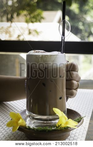 Hand on iced coffee at balcony wooden table stock photo