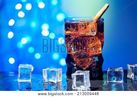 Cola in drinking glass with ice sweet sparkling carbonated drink beverage fast food with big calorie Holiday New year Christmas background spark garland bokeh