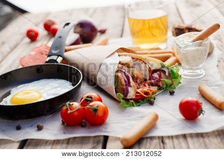 Fast food. Eastern food. Street food. Shawarma is on the wooden table, fried egg and beer. Fried eggs in a frying pan.