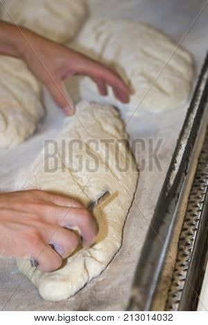 Baker Preparing And Cutting Raw Loaves To Bake In The Oven